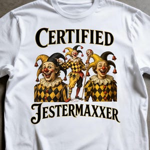 Puede incluir: Camiseta blanca con el texto "CERTIFIED JESTERMAXXER" y un gráfico de tres bufones con trajes de rombos amarillos y negros. Los bufones llevan sombreros con cascabeles y sonríen.