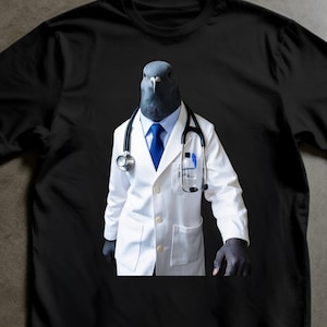 Può includere: T-shirt nero con un piccione che indossa un camice da medico, cravatta blu e stetoscopio. Il piccione ha un'espressione seria. La maglietta è realizzata in un materiale morbido.