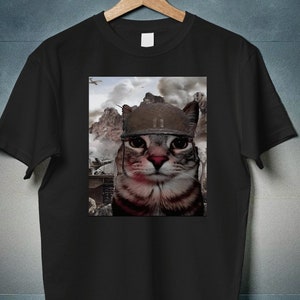 May include: Black t-shirt with a graphic of a cat wearing a military helmet. The cat is looking directly at the viewer. The background is a blurry image of a war scene. The text "35% OFF IF YOU BUY 3 ITEMS CODE: WAVE3" and "40% OFF IF YOU BUY 4 ITEMS CODE: WAVE4" is printed on the image. The text "PRINT Waave" is printed on the bottom right corner of the image.