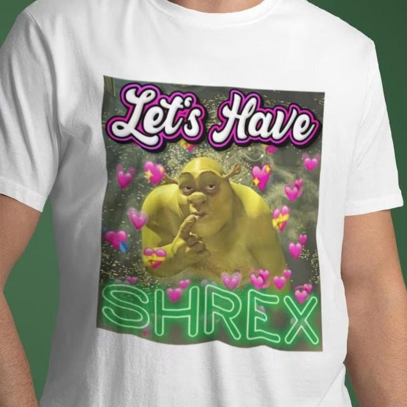 May include: White t-shirt with a green ogre character with the text "Let's Have Shrek" in pink and green.