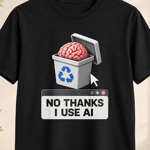Op de afbeelding: Een zwart t-shirt met korte mouwen en een afbeelding van een roze menselijk brein in een grijze prullenbak met een blauw recyclingsymbool. Een witte computermuiscursor wijst naar de bak en de tekst NO THANKS I USE AI staat in een venster.
