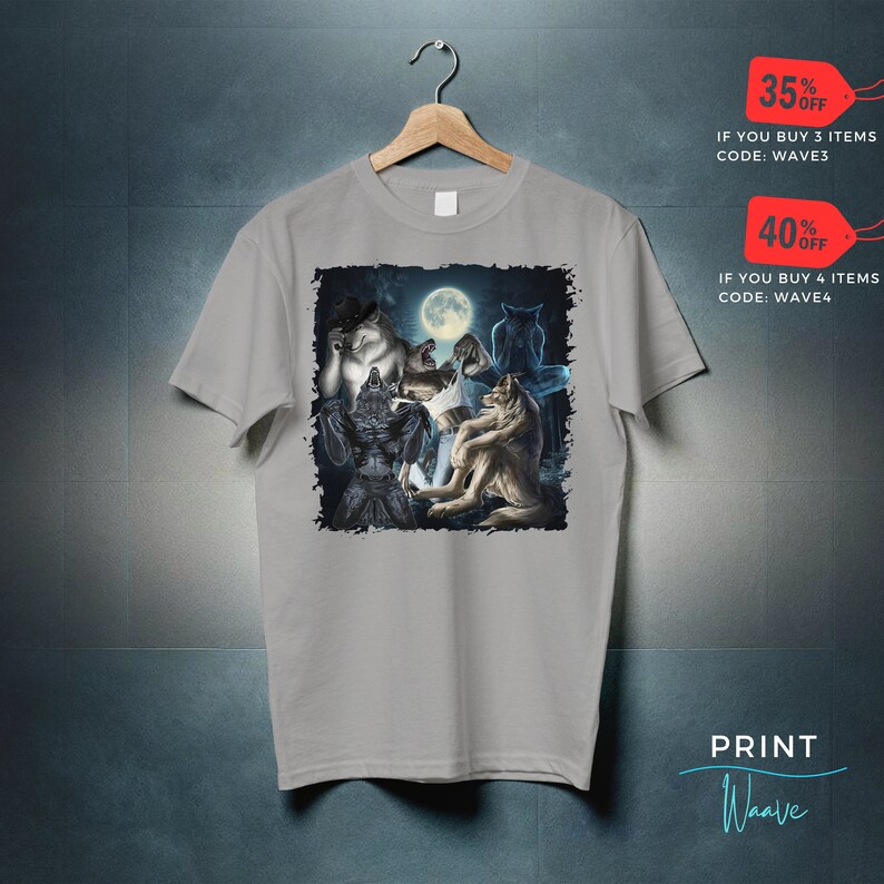 May include: A light gray t-shirt featuring a graphic of werewolves under a full moon. The design includes various werewolf figures in different poses. The shirt is hanging on a wooden hanger.