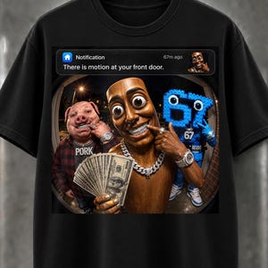 Pode incluir: Uma t-shirt preta com uma impressão gráfica de uma notificação de campainha que diz "There is motion at your front door." A imagem mostra um porco, uma figura de madeira e um personagem azul de blocos segurando dinheiro e usando joias.