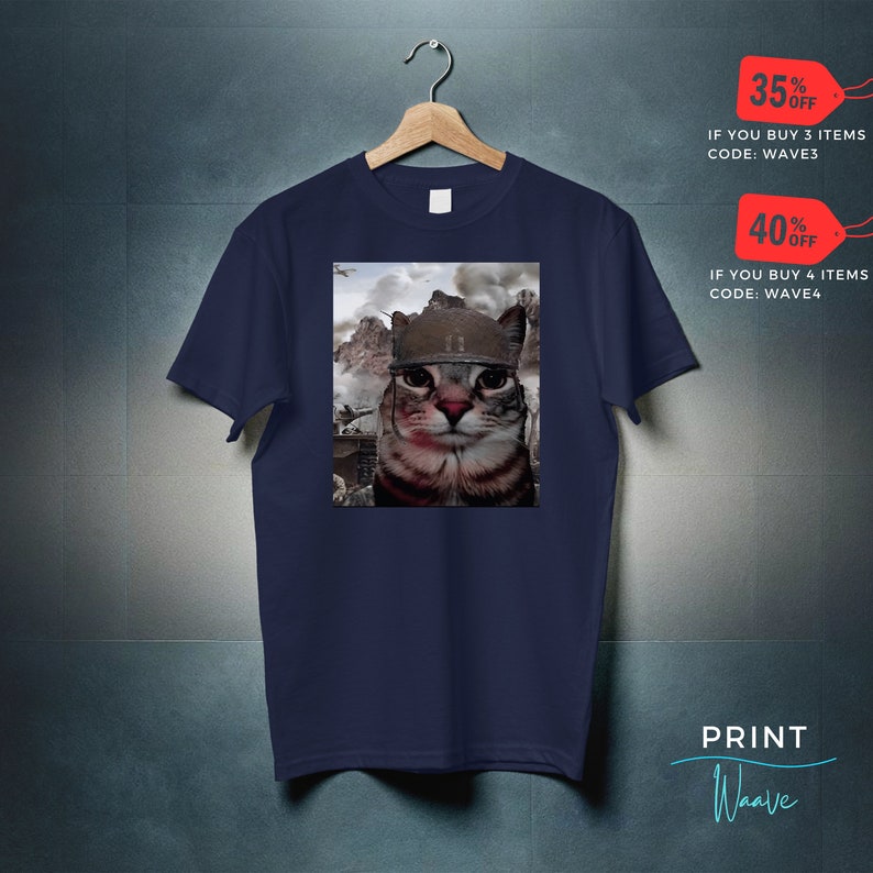 May include: A navy blue t-shirt with a graphic of a cat wearing a military helmet. The cat is looking directly at the viewer. The background of the graphic is a war scene. The text "35% OFF IF YOU BUY 3 ITEMS CODE: WAVE3" and "40% OFF IF YOU BUY 4 ITEMS CODE: WAVE4" is printed on the image. The text "PRINT Waave" is printed in the bottom right corner of the image.