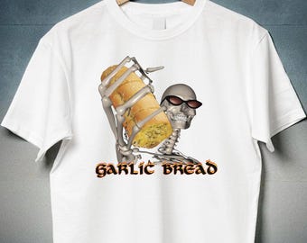 Może przedstawiać: Biały t-shirt z krótkim rękawem z grafiką przedstawiającą szkielet w czarnych okularach przeciwsłonecznych, trzymający bochenek chleba czosnkowego. Pod szkieletem znajduje się napis GARLIC BREAD stylizowaną czcionką z ognistą pomarańczowo-żółtą obwódką.