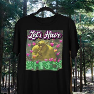 May include: Black t-shirt with a green ogre character with the text "Let's Have Shrex" in pink and green letters.