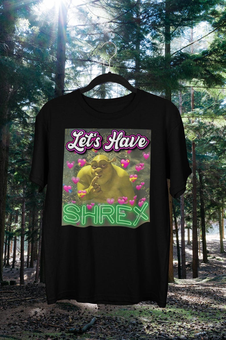 May include: Black t-shirt with a green ogre character with the text "Let's Have Shrex" in pink and green letters.