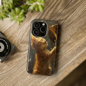 May include: A phone case with a cute orange tabby kitten playing a cymbal. The kitten is looking up at the cymbal with a playful expression. The case is made of a durable material and has a clear, glossy finish.