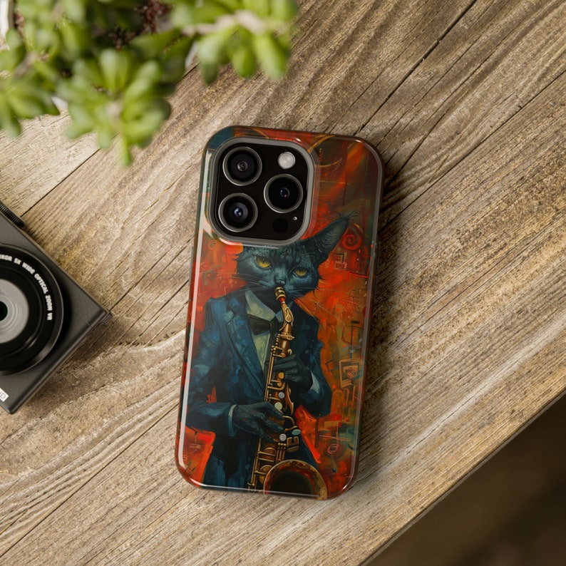 May include: A black cat wearing a tuxedo plays a saxophone. The phone case has a colorful abstract background with red, orange, and yellow hues.