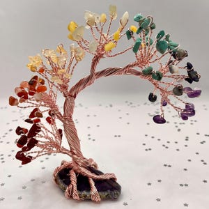 Peut inclure: Une sculpture d'arbre en fil de cuivre avec des feuilles de pierres précieuses colorées. Les pierres précieuses sont disposées en arc-en-ciel, avec du rouge, de l'orange, du jaune, du vert et du violet. L'arbre est monté sur une base en pierre violet foncé.