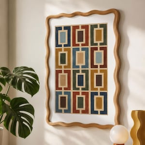 May include: A rectangular wall art piece in a light wood wavy frame featuring a grid of colorful rectangles in shades of blue, red, yellow, and brown. The artwork is displayed on a wall above a wooden surface with books and a small lamp.