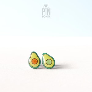 May include: A pair of avocado-shaped earrings with green and yellow enamel. The earrings have a small orange and green detail in the center.