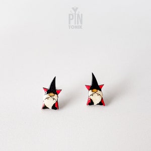 May include: A pair of black and red gnome earrings with a white face and a black hat. The earrings are made of polymer clay and are about 1 inch in size.