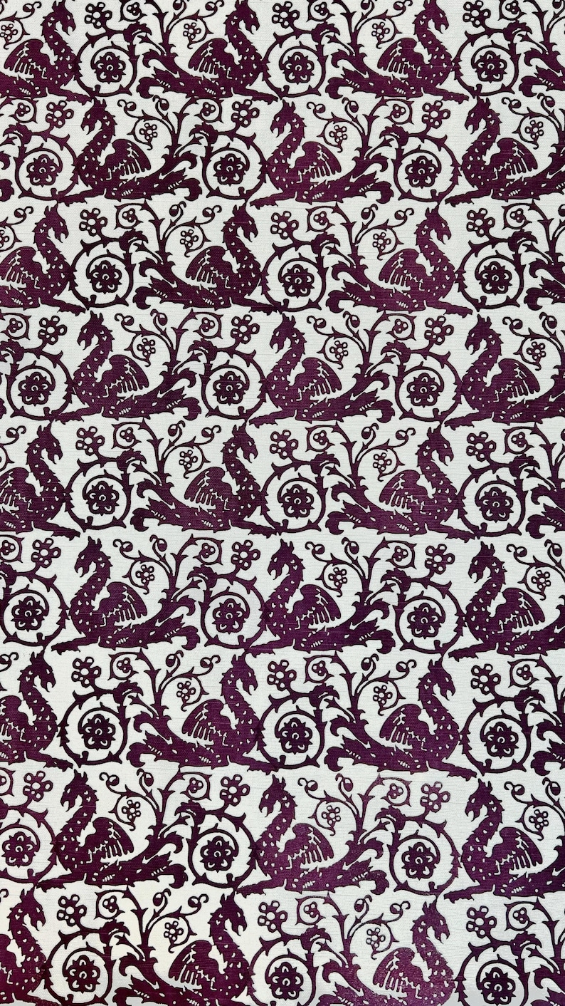 May include: A repeating pattern featuring a stylized dragon design in a deep purple hue against a white background. The dragons are depicted with wings and are interspersed with floral and scroll elements, creating a medieval aesthetic.