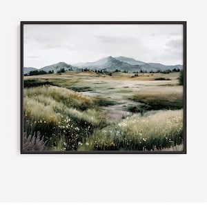 May include: A framed watercolor landscape painting. The artwork depicts a serene meadow with tall grasses, wildflowers, and a winding path leading to distant mountains under a cloudy sky. The color palette is soft, with muted greens, yellows, and blues.