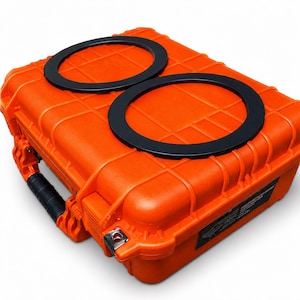 May include: An orange, rugged, rectangular case with a black handle and two black circular rings on top. The case has a textured surface and metal latches. The case is designed for protection and storage.