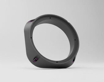May include: A matte dark gray circular mounting ring with a wide, contoured frame. The component features several small, evenly spaced screw holes along the inner rim and three distinct recessed points accented with small purple metal fasteners.