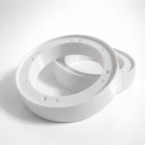 May include: Two white, circular objects with multiple small holes around the edges. The objects are stacked, with one partially inside the other. The objects have a smooth, matte finish and are set against a white background.