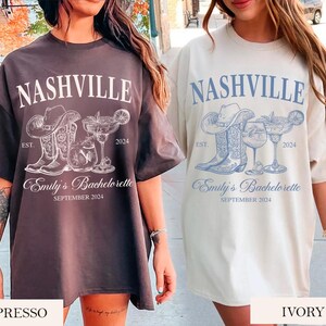 May include: Two women wearing oversized t-shirts with a graphic design of boots, a margarita glass, and the text "Nashville, Est. 2024, Emily's Bachelorette, September 2024". The shirt on the left is brown and the shirt on the right is ivory.
