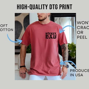 May include: A red short-sleeve t-shirt with the text "HOCKEY DAD" printed on the front. The shirt is made of soft cotton and is produced in the USA. The print won't crack or peel.
