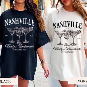 May include: Two black and white t-shirts with a graphic of three cocktail glasses and the text "Nashville" and "Emily's Bachelorette" on them. One shirt is black and the other is ivory.