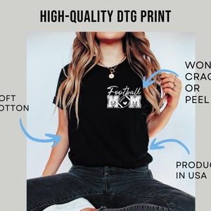 May include: A black t-shirt featuring a white graphic on the chest that reads Football MOM with a football icon. The image includes text labels stating HIGH-QUALITY DTG PRINT, SOFT COTTON, WON'T CRACK OR PEEL, and PRODUCED IN USA.