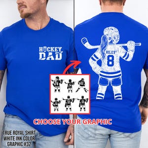 Pode incluir: T-shirts azuis reais com gr&aacute;ficos brancos. Uma camisa diz "HOCKEY DAD" e apresenta uma sele&ccedil;&atilde;o de gr&aacute;ficos de jogadores de h&oacute;quei. A outra camisa mostra um jogador de h&oacute;quei com o nome "RILEY" e o n&uacute;mero "8". O texto "CHOOSE YOUR GRAPHIC" tamb&eacute;m &eacute; vis&iacute;vel.