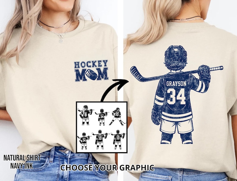 May include: A cream-coloured t-shirt with a navy blue "Hockey Mom" graphic on the front. The back features a navy blue hockey player jersey with the name "Grayson" and the number "34". Includes a graphic selection.
