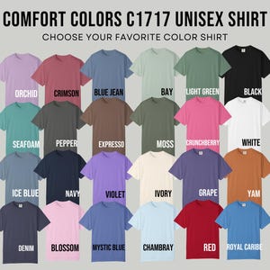 May include: A display of Comfort Colors C1717 unisex shirts in various colors, including orchid, crimson, blue jean, and black. The text "CHOOSE YOUR FAVORITE COLOR SHIRT" is above the shirts. Other colors include seafoam, navy, and red.
