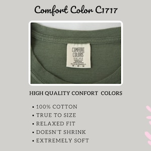 May include: Close-up of an olive green t-shirt collar with a Comfort Colors tag. The image also includes the text "HIGH QUALITY CONFORT COLORS", and bullet points that read "100% COTTON", "TRUE TO SIZE", "RELAXED FIT", "DOESN'T SHRINK", and "EXTREMELY SOFT".