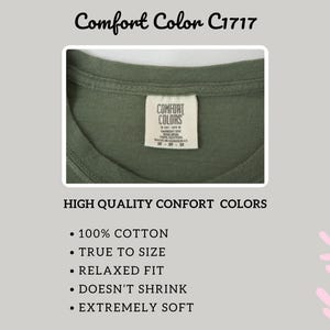 May include: An olive green t-shirt featuring a white interior neck label with the text Comfort Colors, Est. 1975, 100% Cotton, Made in Honduras, and size M. The image includes text listing features such as 100% cotton, true to size, and relaxed fit.