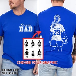 May include: Royal blue t-shirt with the text "Soccer DAD" in white. The back of the shirt features a soccer player graphic with the name "KATHIE" and the number "23". A graphic with soccer player options is also shown. The shirt is made with white ink.