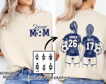 May include: A cream-coloured t-shirt with navy blue text and graphics. The front displays "Soccer Mom" with a football. The back shows two soccer players with names and numbers. Graphic options are shown below the shirt.