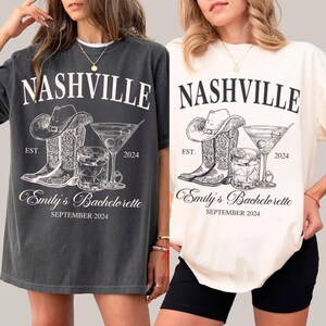 May include: Two gray and white t-shirts with a graphic design of cowboy boots, a cocktail glass, and the text "Nashville Est. 2024 Emily's Bachelorette September 2024".