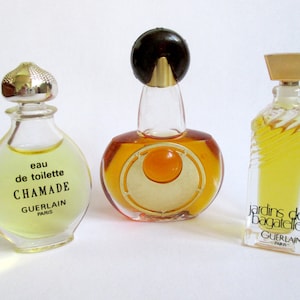 Könnte beinhalten: Drei kleine Glasflaschen mit Parfüm, mit goldenen und silbernen Kappen. Die Flaschen sind mit einer gelben Flüssigkeit gefüllt. Die Etiketten auf den Flaschen lauten "eau de toilette Chamade Guerlain Paris" und "Jardins de Bagatelle Guerlain Paris".
