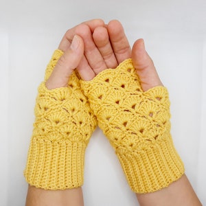 May include: A pair of yellow crocheted fingerless gloves with a lacy pattern. The gloves are made with a soft yarn and have a comfortable fit.
