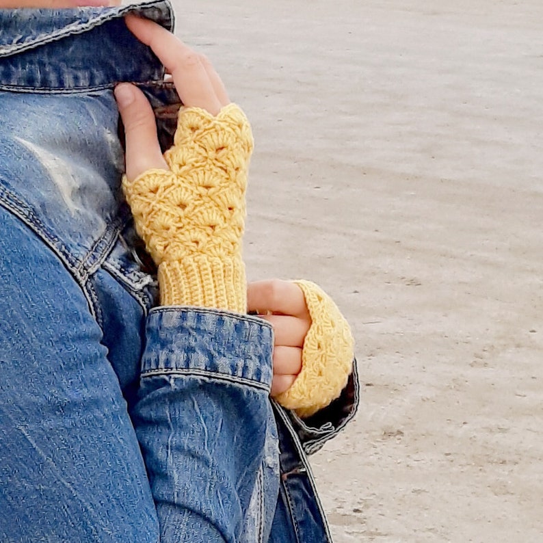 May include: A pair of yellow crocheted fingerless gloves. The gloves have a lacy pattern and are made with a soft yarn.