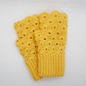 May include: A pair of yellow crocheted fingerless gloves with a scalloped edge and a textured pattern.