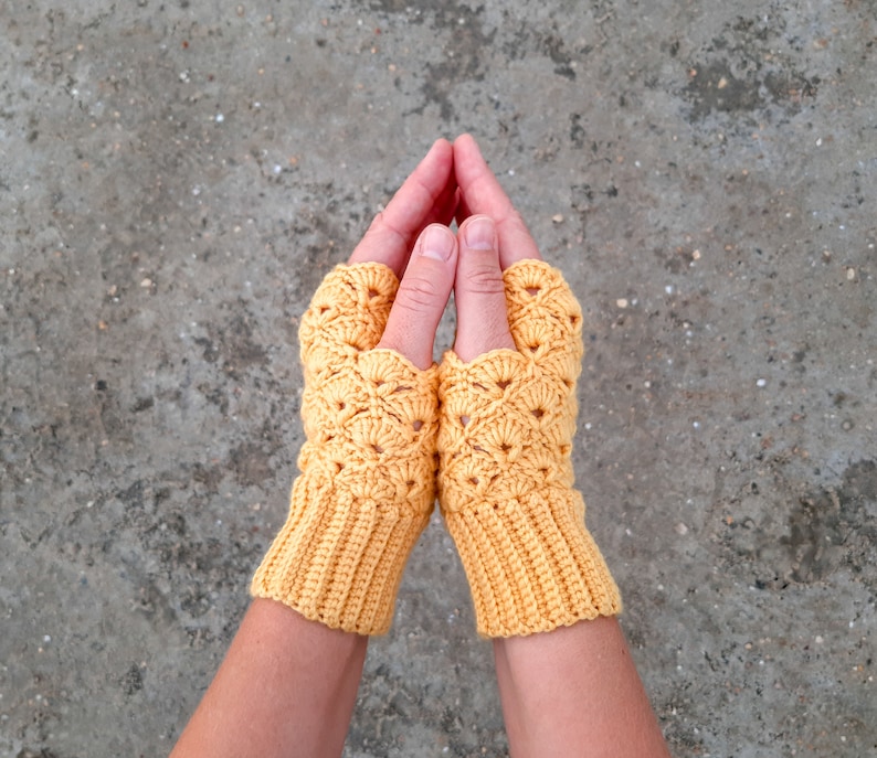 May include: A pair of yellow crocheted fingerless gloves with a lacy pattern.