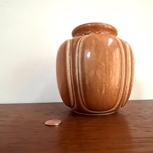 May include: A brown ceramic vase with a ribbed design. The vase has a glossy finish and is decorated with white lines.
