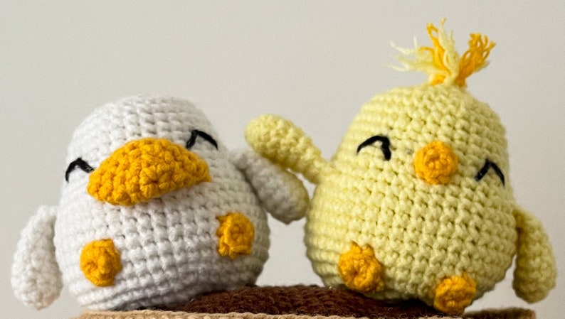 Crochet PDF Pattern for little baby yellow chicken with with yellow orange feathers and white baby duck with orange beak. These two baby animals are joined with crocheted chain to be used as car rear mirror hanger, or to be hanged anywhere in general