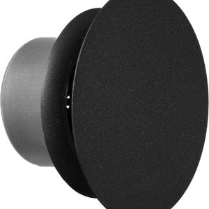 Può includere: Un'applique da parete nera e circolare con superficie strutturata. Presenta una base cilindrica e due paralumi sovrapposti a forma di disco. Il design è moderno e minimalista.