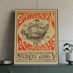 Może przedstawiać: Oprawiony plakat z koncertu w stylu vintage w pomarańczowo-kremowej kolorystyce, przedstawiający sterowiec. Jest on umieszczony na ciemnozielonej szafce ze złotymi nogami, obok małej rośliny doniczkowej i nowoczesnej lampy. Szafka ma około 150 cm długości.