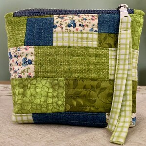 May include: A green and blue patchwork zippered pouch with a white and green gingham strap.