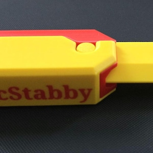 May include: A yellow and red plastic toy knife with a handle that says "McStabby" in red letters.