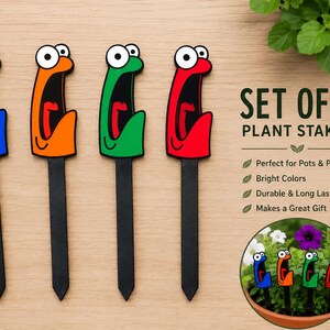 May include: A set of four plant stakes in blue, orange, green, and red, each featuring a cartoon face with a wide-open mouth. The text reads SET OF 4 PLANT STAKES, Perfect for Pots & Planters, Bright Colors, Durable & Long Lasting, Makes a Great Gift.