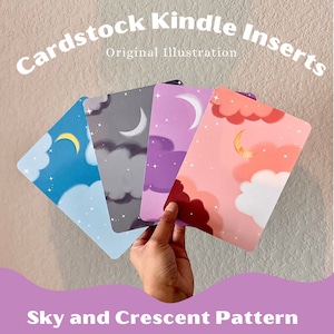 May include: Four cardstock Kindle inserts featuring a sky and crescent moon design. The inserts are in blue, grey, purple, and pink.