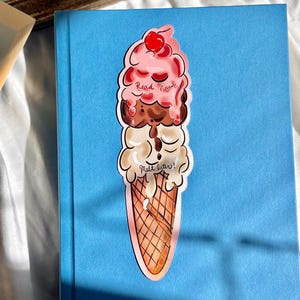 Pu&ograve; includere: Un segnalibro a forma di cono gelato colorato con il testo "Read Now" e "Melt Later!" su di esso. Il segnalibro &egrave; fatto di carta e ha una finitura lucida.