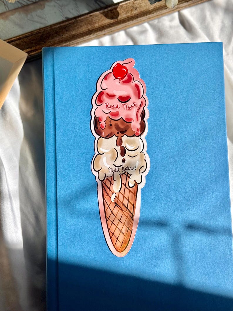 Pu&ograve; includere: Un segnalibro a forma di cono gelato colorato con il testo "Read Now" e "Melt Later!" su di esso. Il segnalibro &egrave; fatto di carta e ha una finitura lucida.