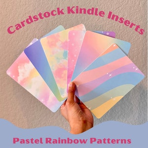 May include: A set of six pastel rainbow patterned cardstock inserts for a Kindle e-reader. The inserts feature a variety of designs, including clouds, stars, and stripes.